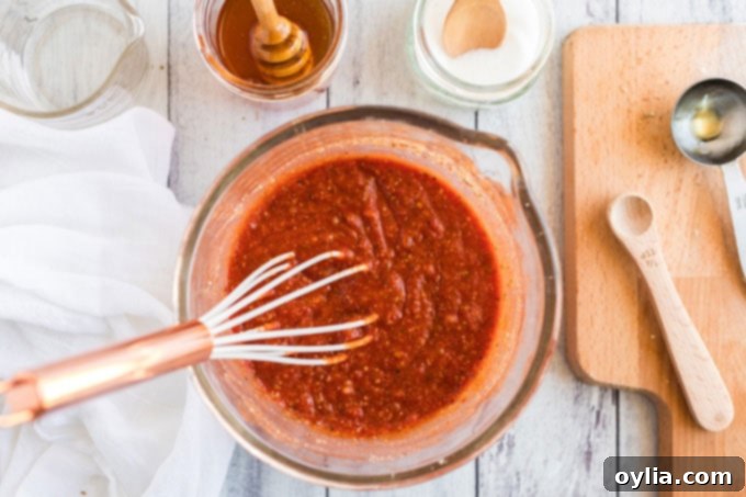 Whisking the homemade pizza sauce ingredients together in a bowl.