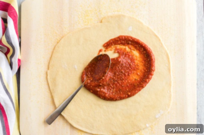 Spreading vibrant homemade pizza sauce evenly over fresh pizza dough.