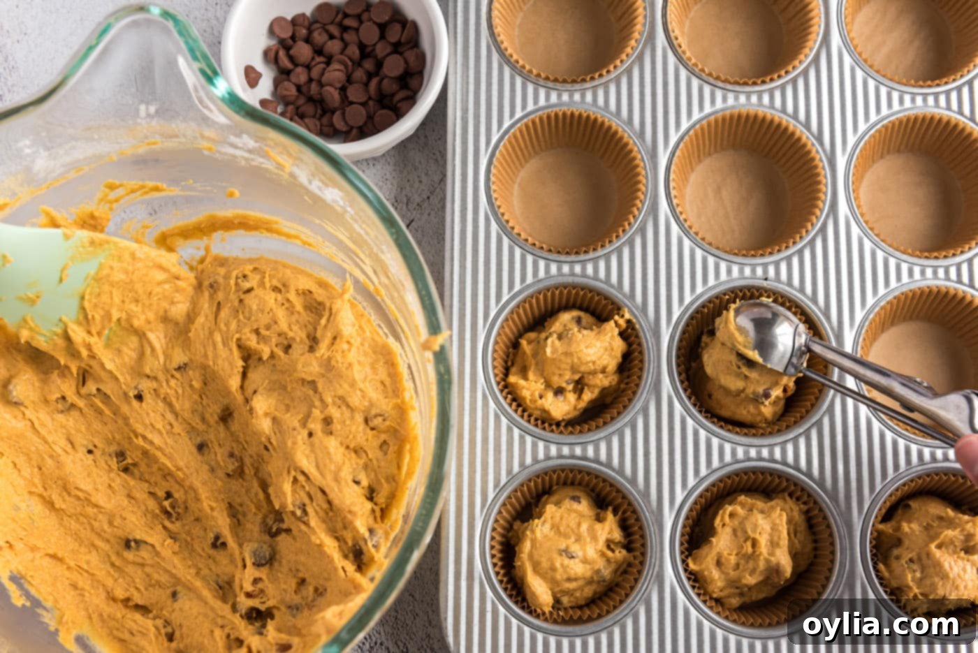 Scooping pumpkin muffin dough into prepared muffin pan