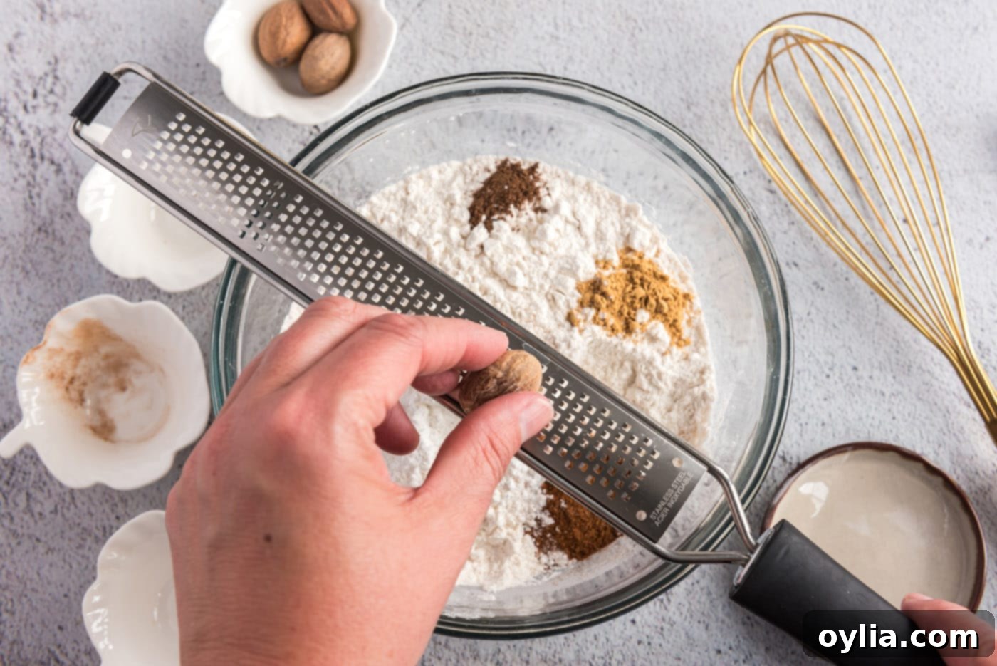 Grating fresh nutmeg over flour mixture and spices in a bowl