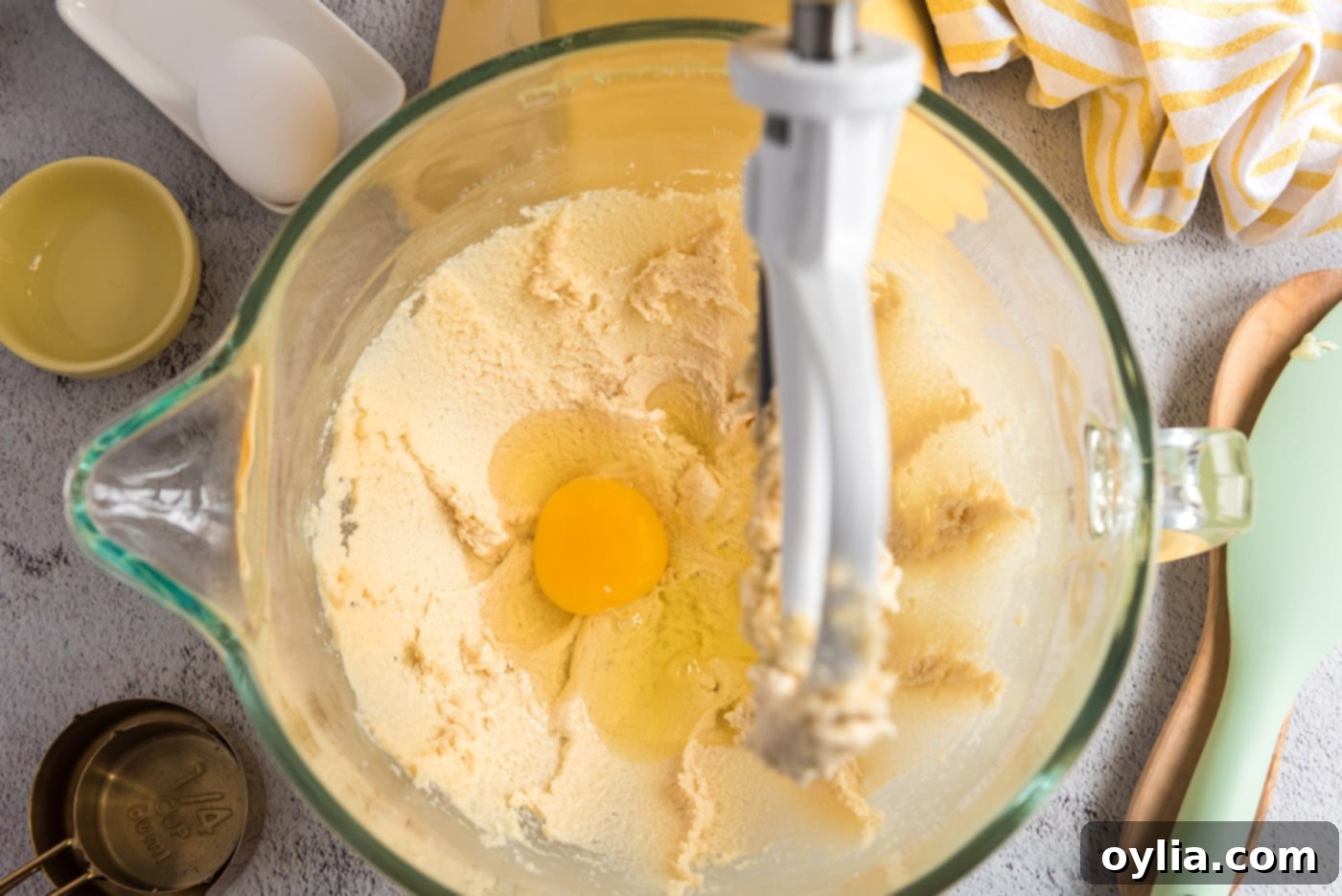 Adding eggs one by one to the creamed butter and sugar mixture