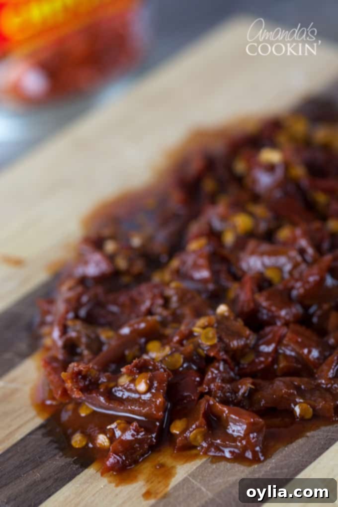 A close up of chopped chipotle chili peppers on a wooden cutting board.