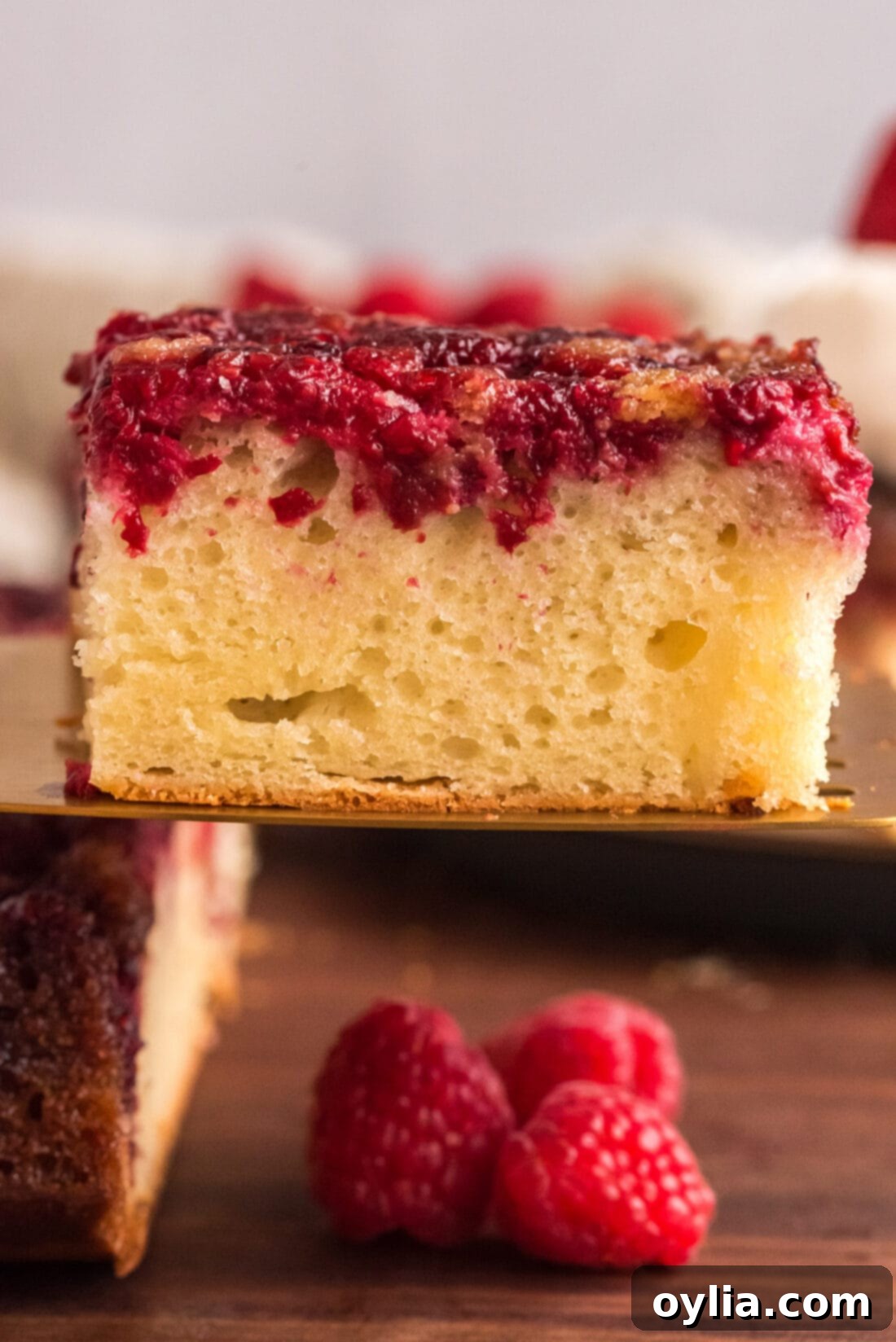 Square of Raspberry Upside Down Cake lifted up on a spatula