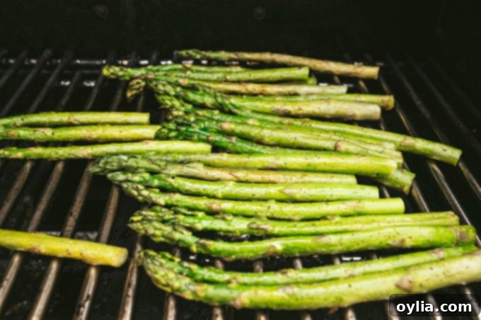 Perfectly grilled asparagus spears arranged neatly on the hot grates of an outdoor grill.