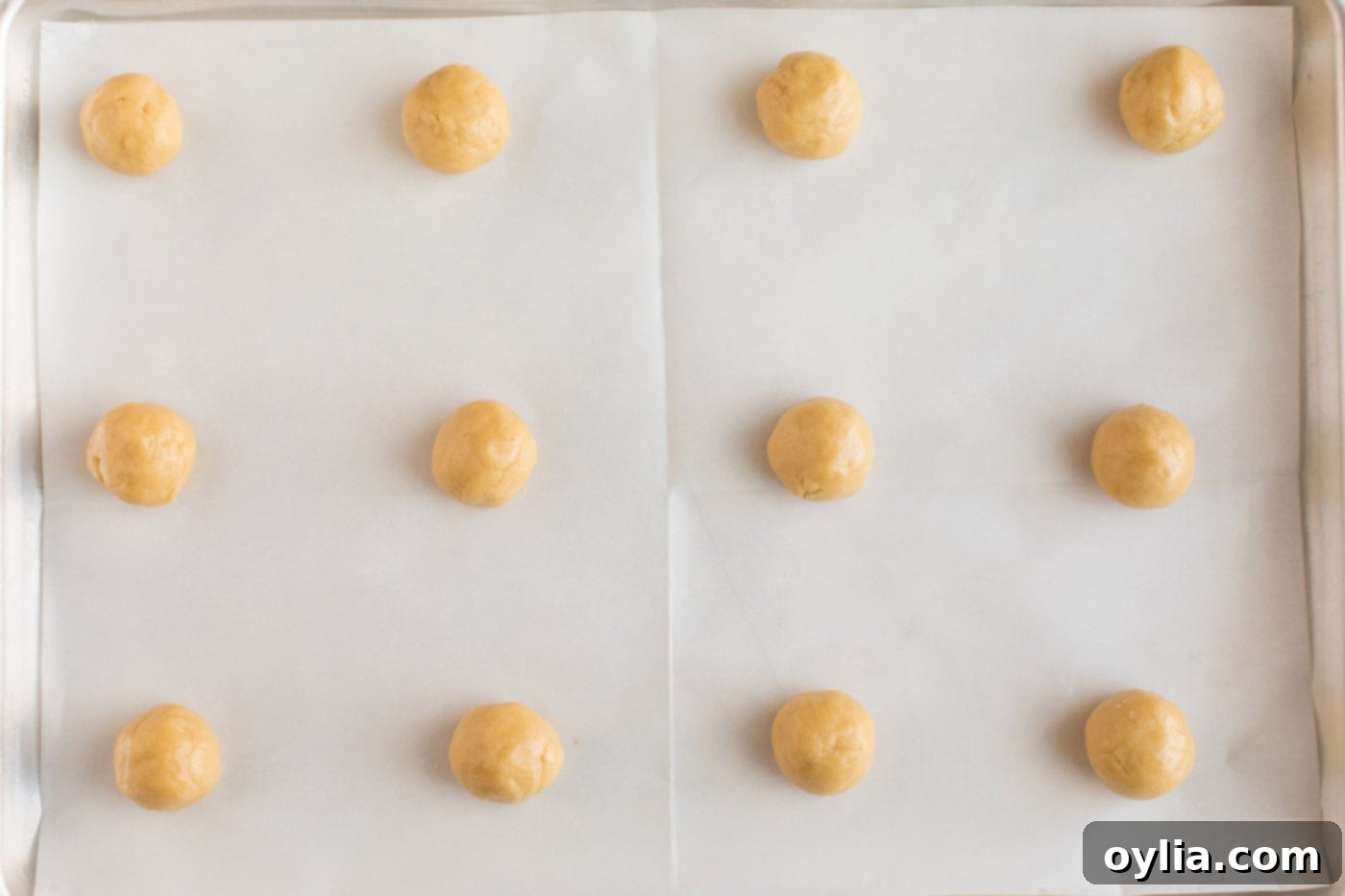 Small, uniformly rolled balls of Italian Anisette Cookie dough arranged on an ungreased baking sheet, perfectly spaced and ready for the oven.