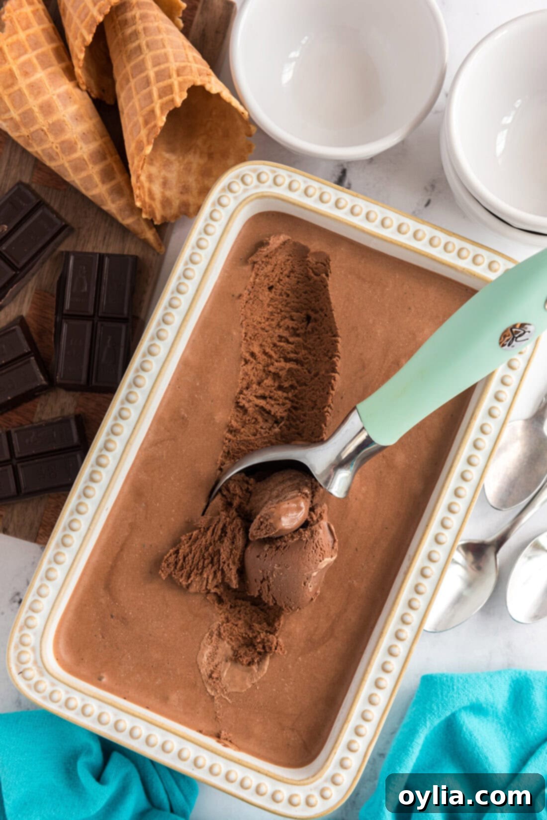 Container of Homemade Chocolate Ice Cream with an ice cream scooper in it, showcasing its creamy texture