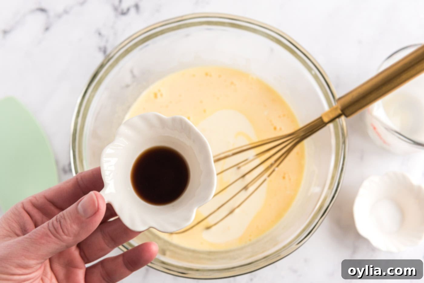 Adding vanilla extract to the whisked eggs, sugar, and heavy cream mixture