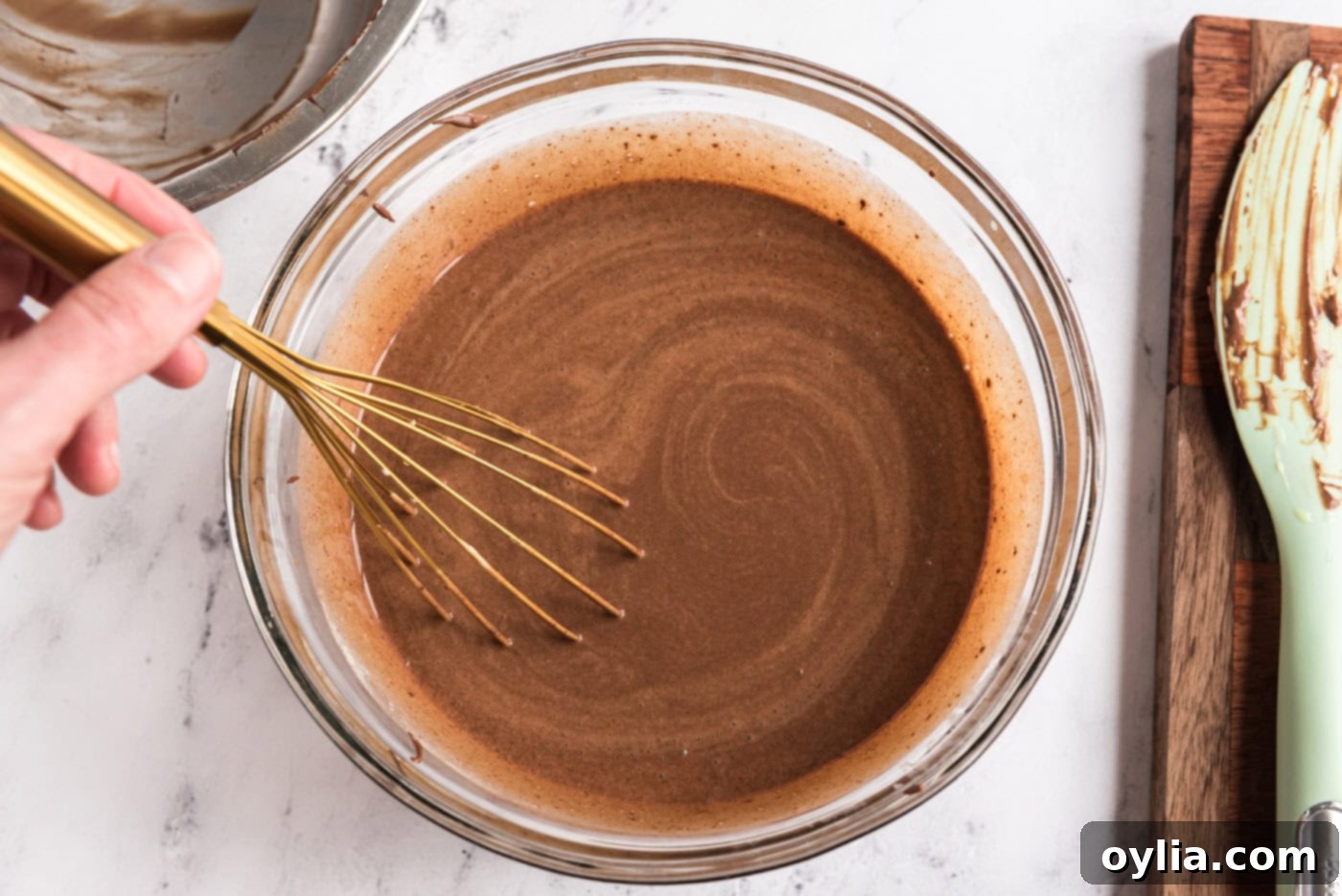 Smooth chocolate ice cream base in a bowl with a whisk, showing its rich color