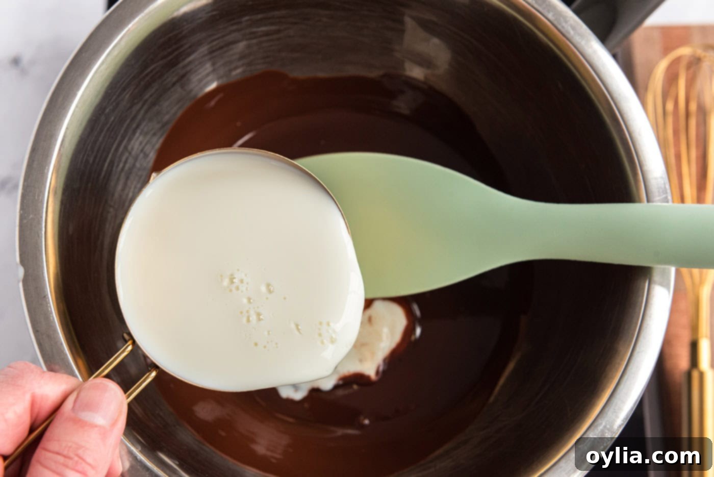 Whisking milk into melted chocolate in a large mixing bowl