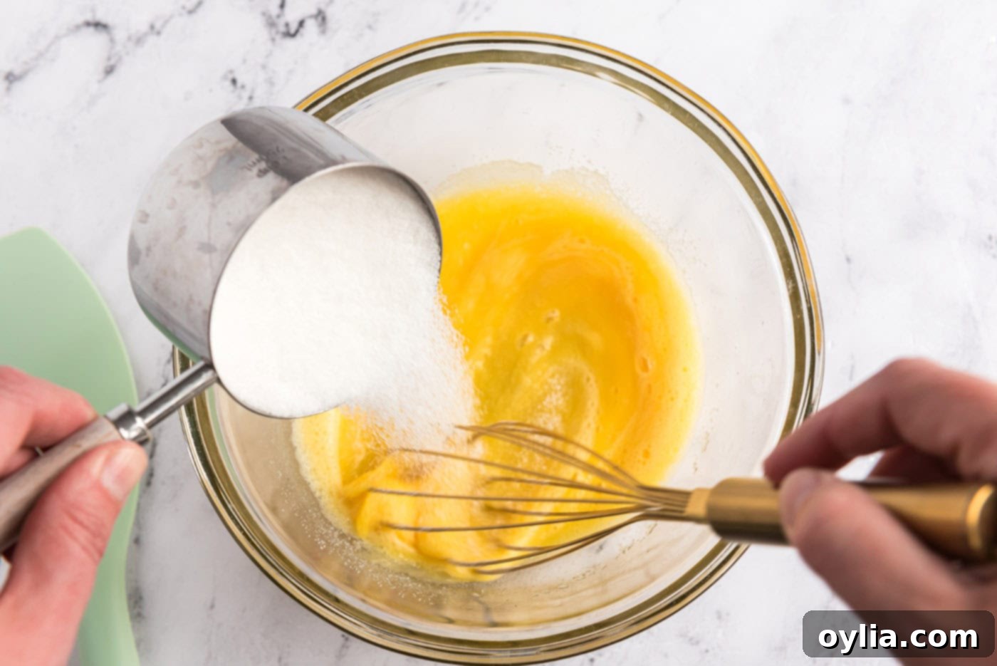 Whisking granulated sugar into eggs in a mixing bowl