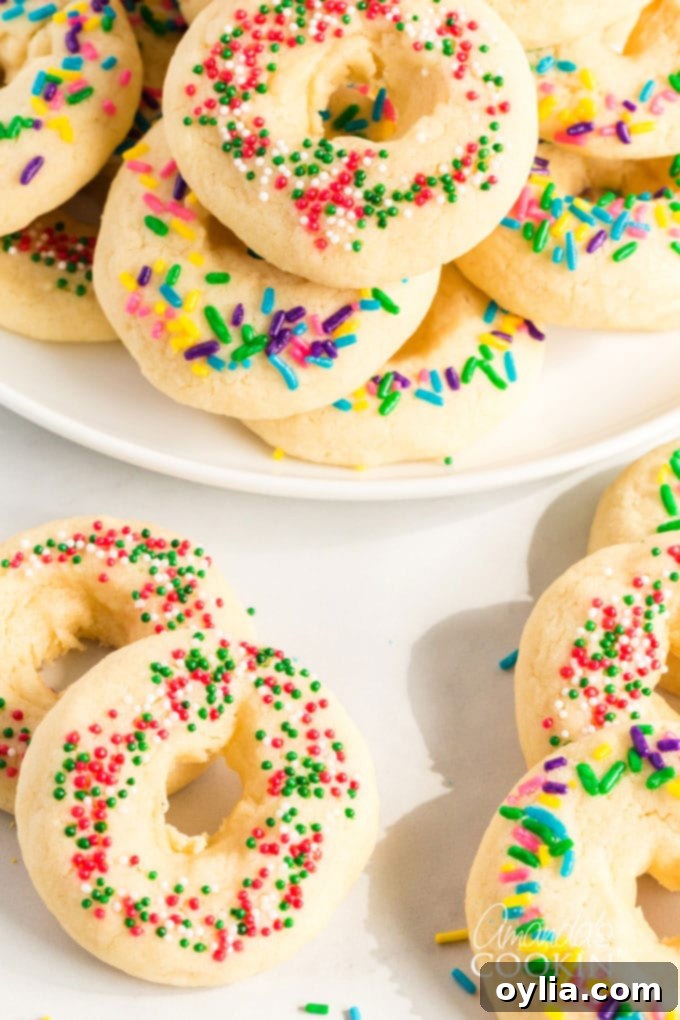 A delicious buttery sugar cookie with a pretty presentation. These soft cookies would be great for a birthday party, Cinco de Mayo celebrations, or just when you want a chewy sugar cookie. Pretty Mexican cookie rings on table and white plate with colorful sprinkles