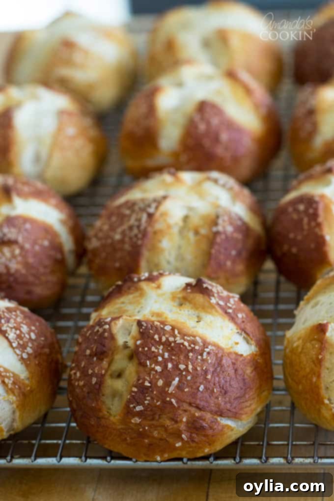 Three rows of freshly baked pretzel rolls laying on a wire cooling rack.