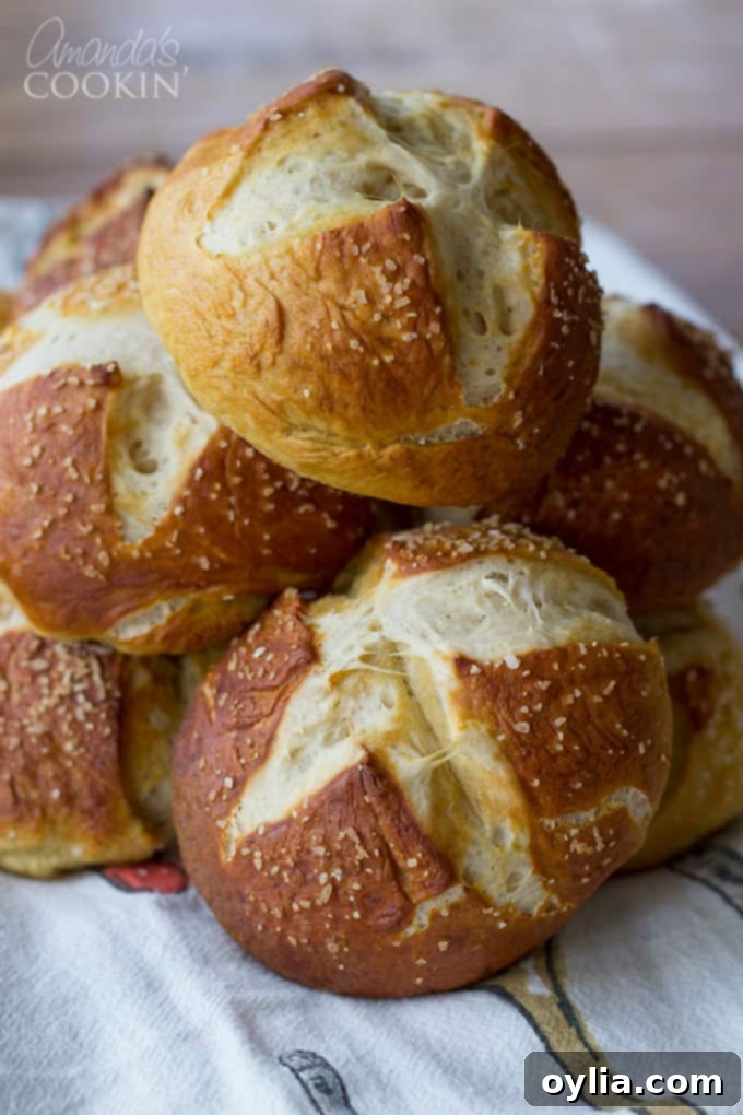 A close up of warm, soft pretzel rolls resting in a bowl, ready to be served.