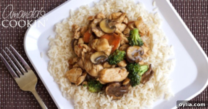 A close-up of chicken and mushroom stir fry on a bed of white rice, garnished with green onions.