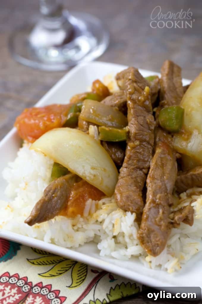 A close up of a white plate with white rice and Chinese pepper steak on top.