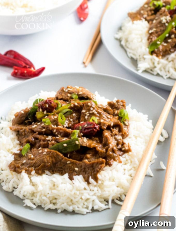 Close-up of a plate of Mongolian Beef with chopsticks, showcasing the rich sauce and tender beef.