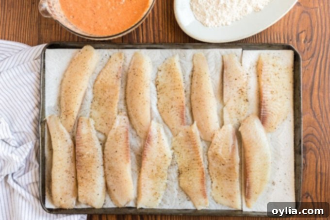 fish strips on paper towels seasoned with salt and pepper