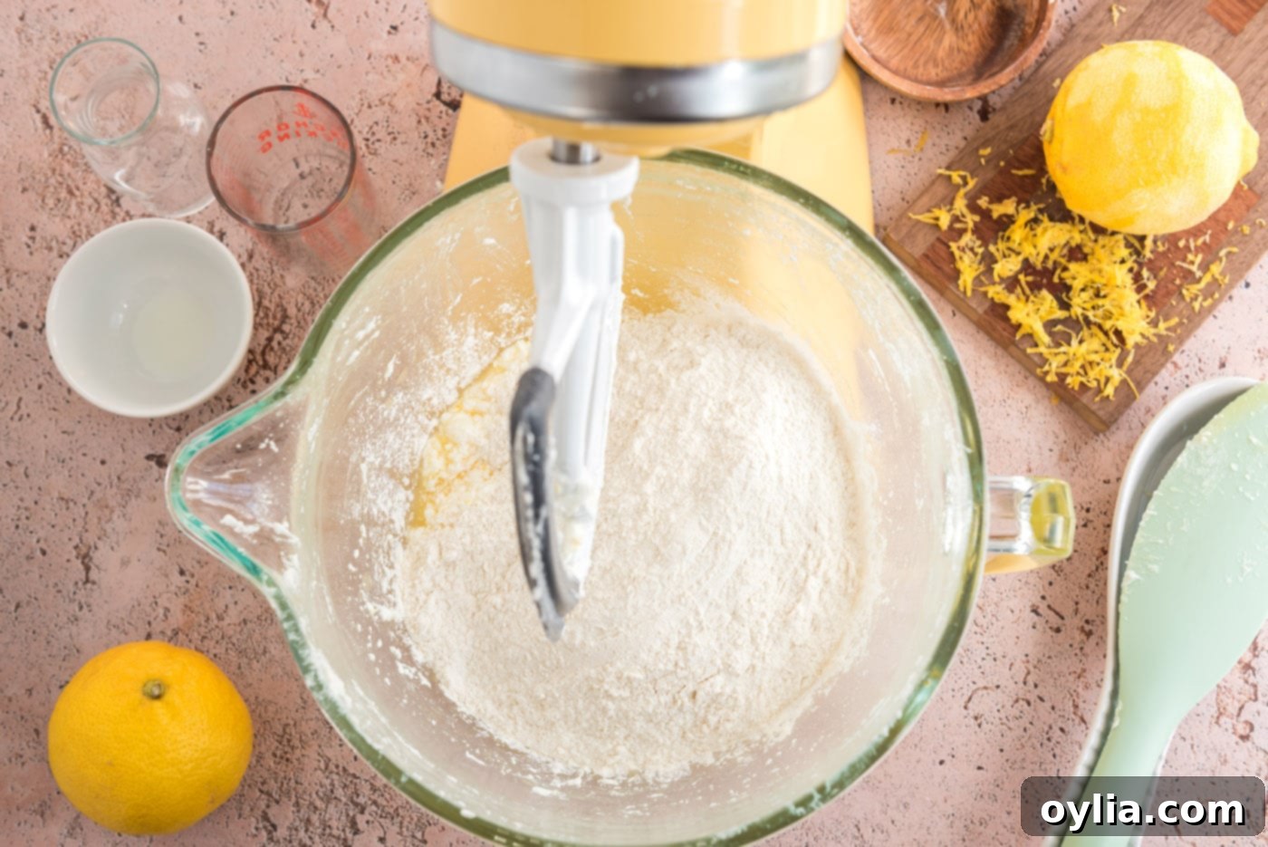 The sifted flour mixture being gently added to the wet ingredients in a stand mixer bowl.