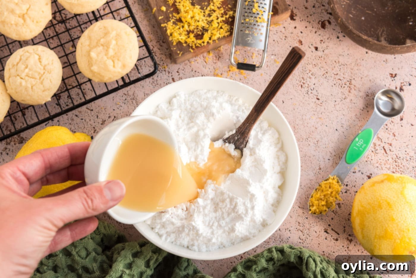 Fresh lemon juice being drizzled into a bowl of powdered sugar, forming the base for the sweet-tart glaze.