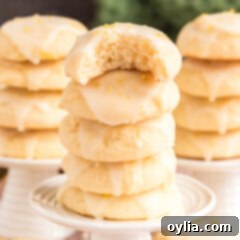 Three stacks of Lemon Drop Cookies with a bite taken off the top cookie, showcasing their soft interior and shiny glaze.