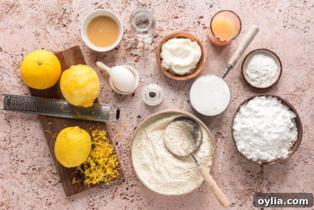 A flat lay of all fresh and dry ingredients for Lemon Drop Cookies, including bright yellow lemons, flour, sugar, eggs, and shortening.