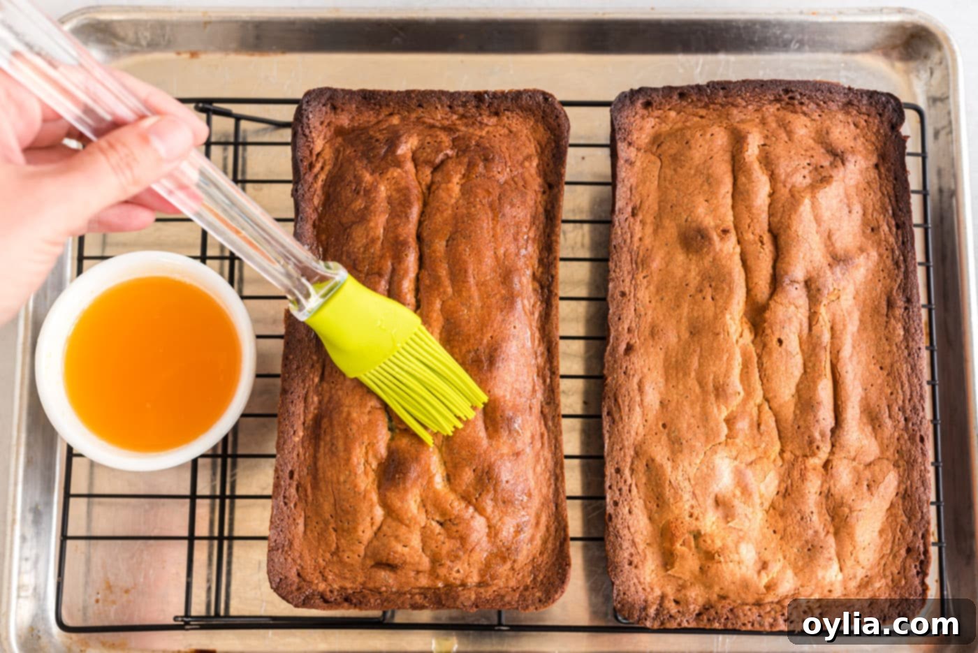 brushing orange pound cake with fresh orange glaze for maximum flavor