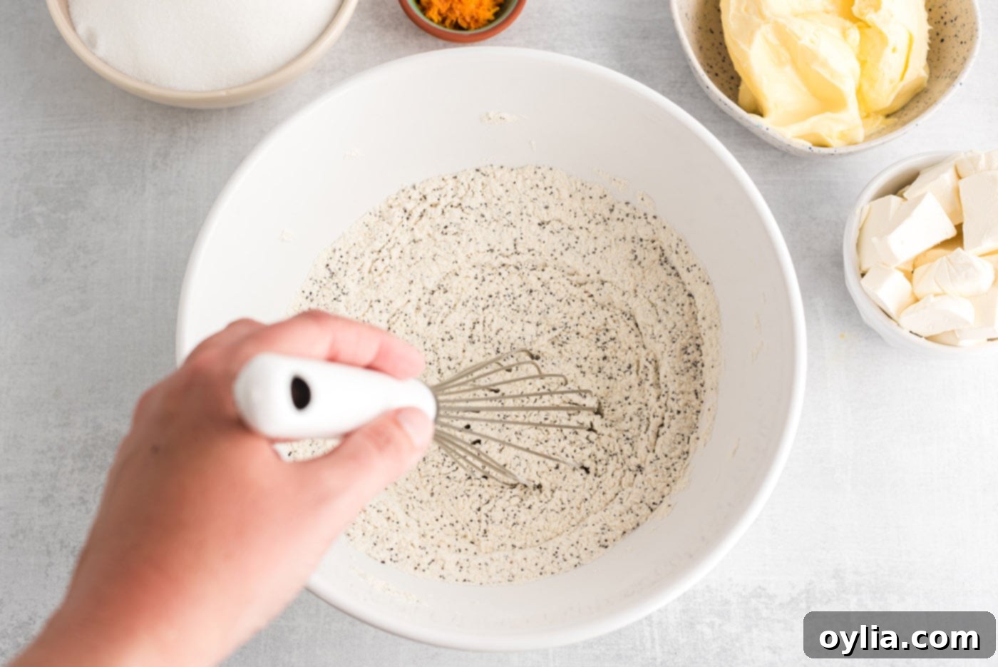 whisking together poppyseed, flour, salt, and baking powder in a bowl for pound cake