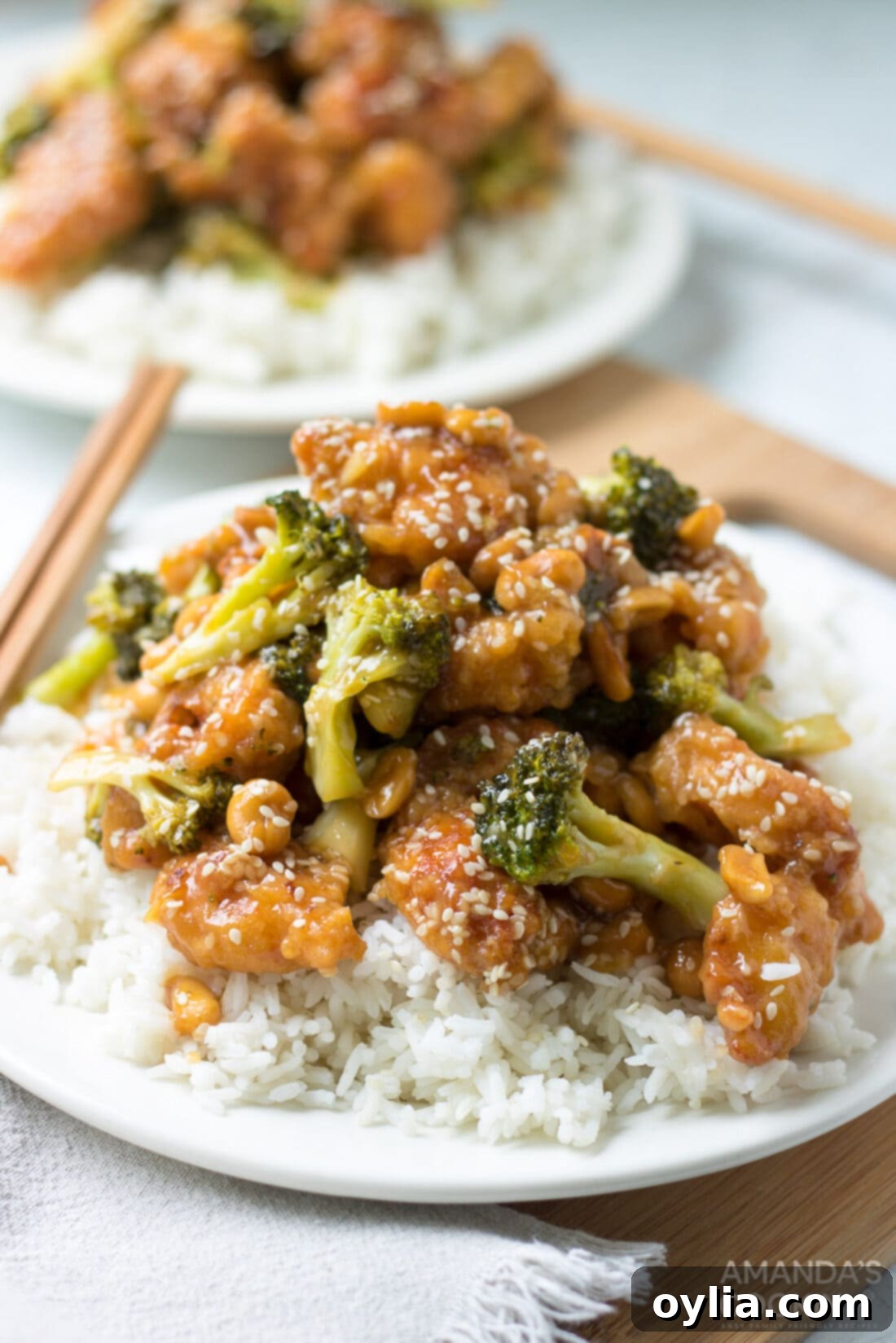 Sesame chicken is complemented by a mixture of diced ginger, red wine vinegar, hoisin sauce, soy sauce, and topped with broccoli and sesame seeds. plate of homemade sesame chicken