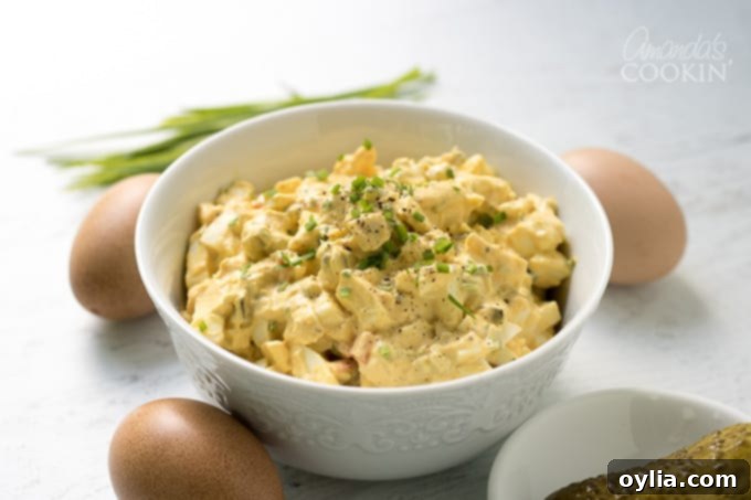 A bowl of egg salad garnished with chives, ready for a gathering.