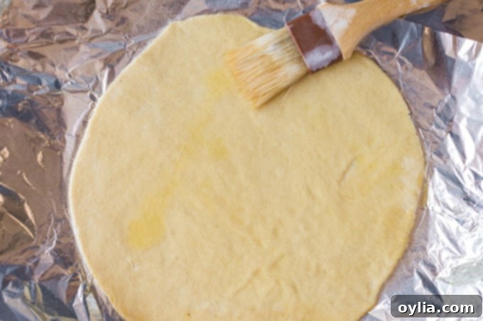 brushing olive oil on pizza dough