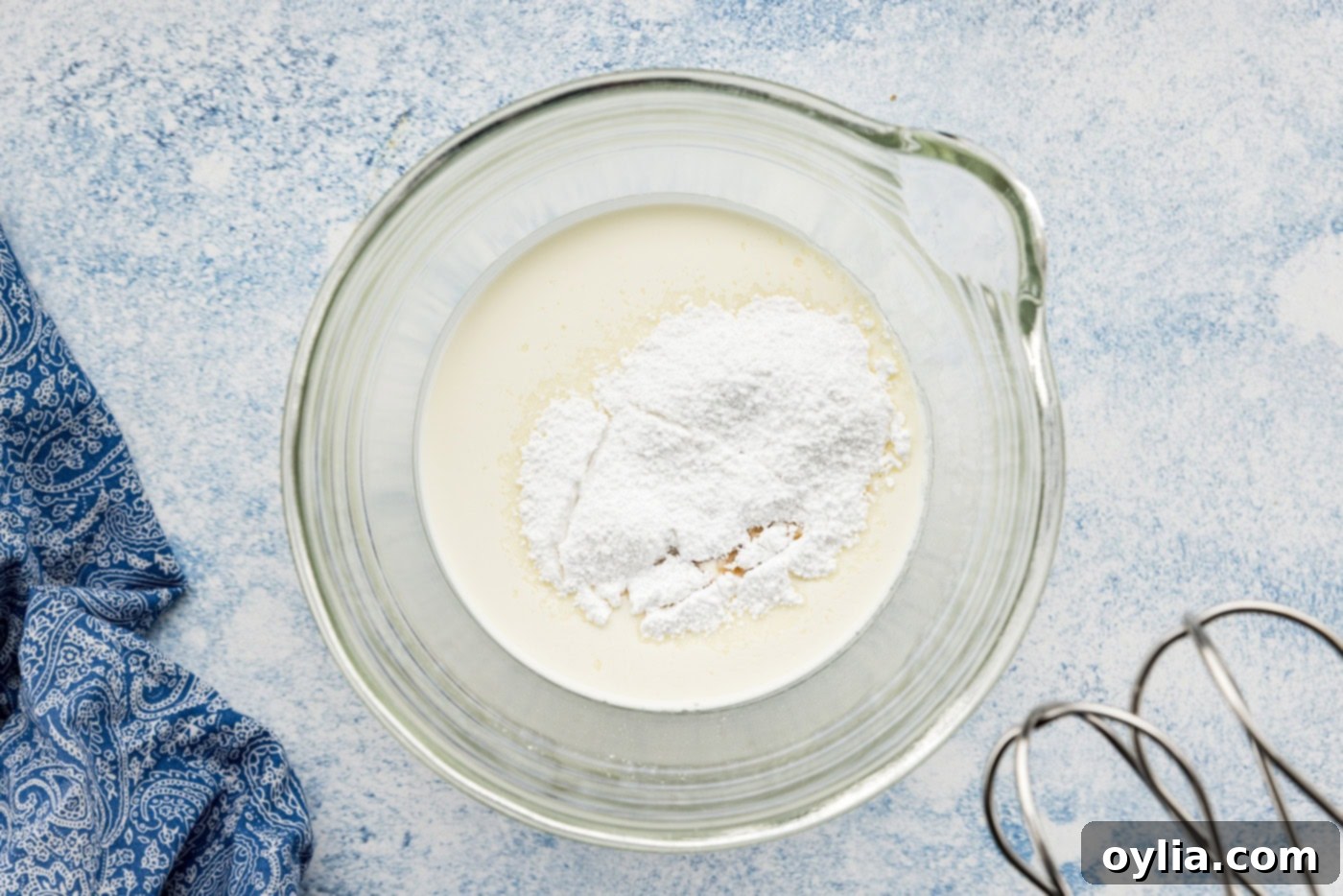 powdered sugar and vanilla extract added to heavy whipping cream in a bowl
