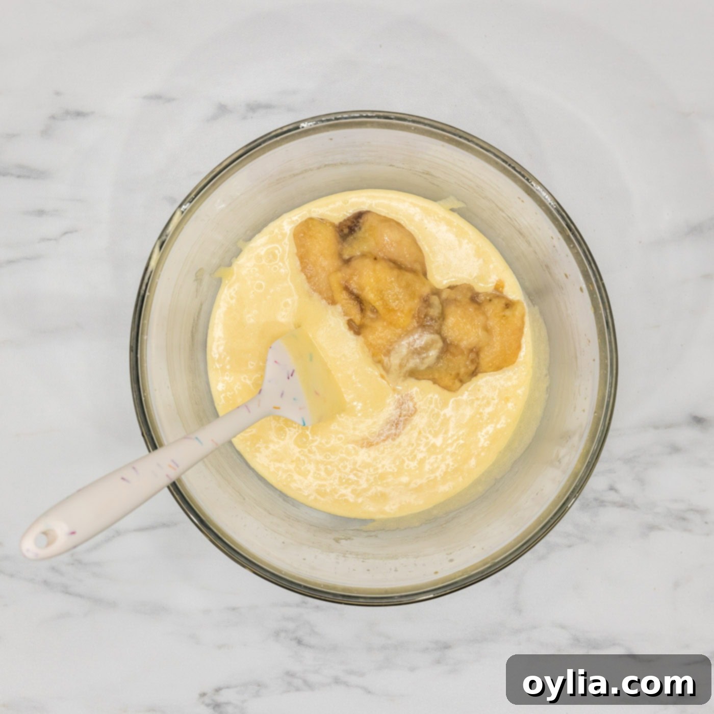 mashed bananas added to bundt cake batter in a bowl