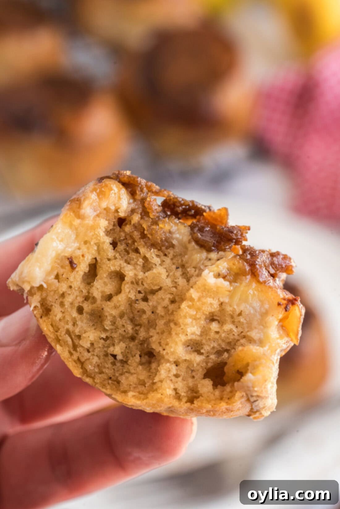 Caramelized Banana Muffins 16 Hand holding up a Banana Upside Down Muffin with two bites taken out