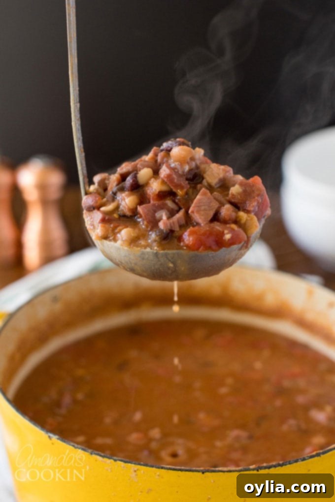 Steaming ladle of hearty ham and bean soup, garnished with fresh parsley