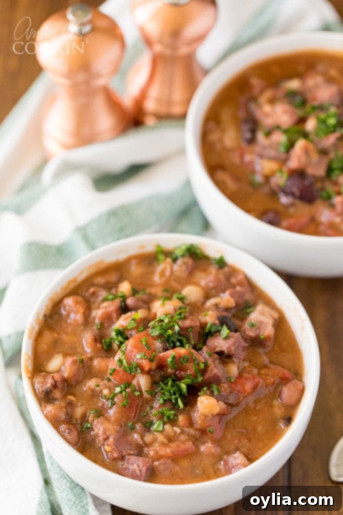 Two bowls of ham and bean soup, garnished with fresh parsley, ready to serve