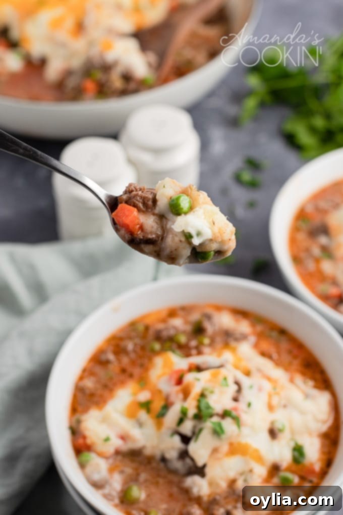 Close-up of a spoonful of Shepherd's Pie showing the tender meat and vegetable mixture beneath the fluffy mashed potato topping.