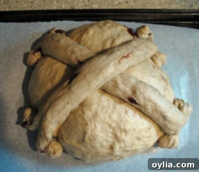 A photo of the remaining dough formed into ropes and intricately placed on top of the dough ball, forming a cross pattern.
