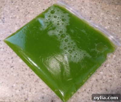 A glass cup filled with green zucchini juice, freshly squeezed from shredded zucchini.