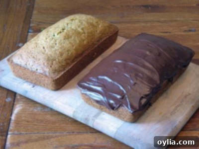 A freshly baked loaf of Morning Glory Zucchini Bread on a cutting board, garnished with a sprig of mint.