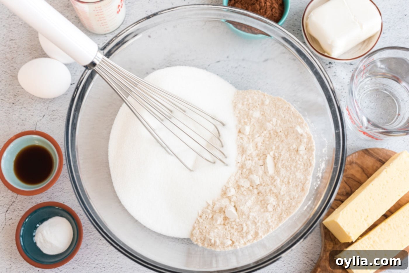 Flour and sugar in a bowl with a whisk, ready for mixing to form the cake's dry ingredients
