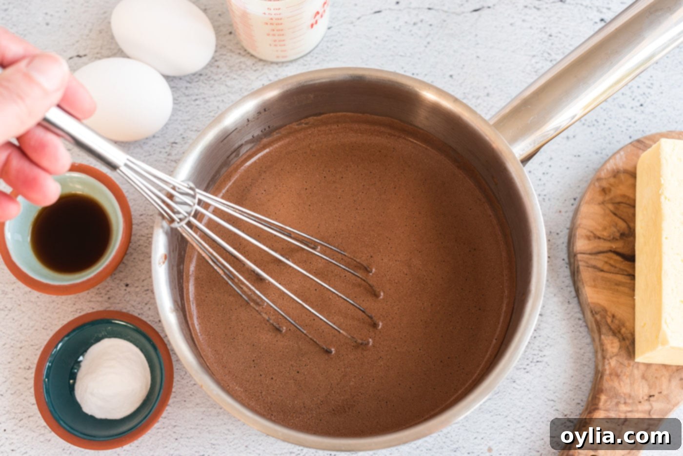 Whisking chocolate, butter, shortening, and water in a saucepan over heat for the cake batter