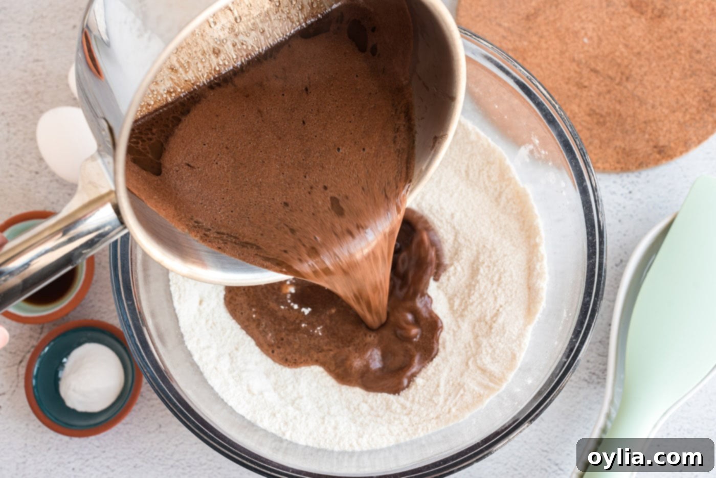 Pouring the hot chocolate mixture into a bowl of dry ingredients for the cake