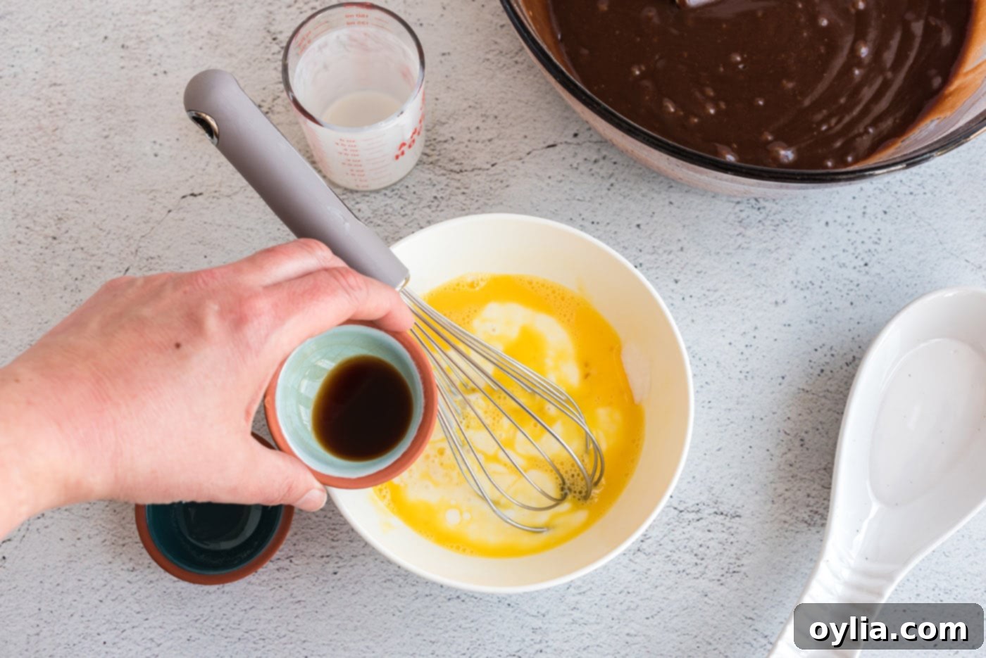 Buttermilk, eggs, baking soda, and vanilla extract being whisked in a bowl for the cake