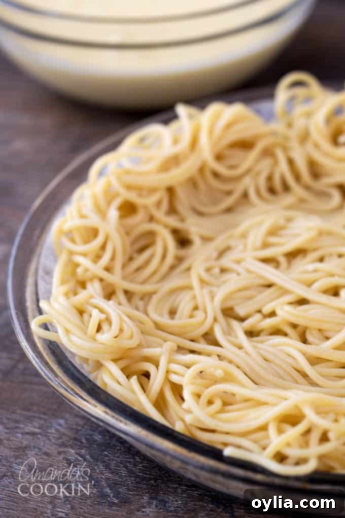 A close up of cooked spaghetti pressed into a pie plate.