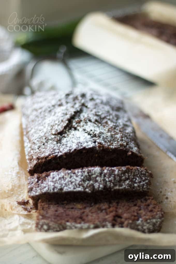 Sliced chocolate zucchini bread with powdered sugar on a plate