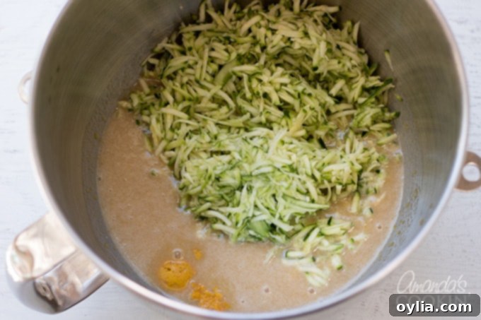 Grated zucchini being stirred into the wet batter