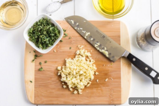 chopped garlic on cutting board with knife and fresh thyme