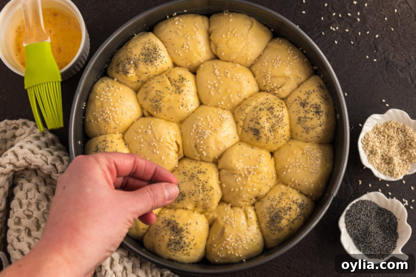 sprinkling bread rolls with poppy seeds and sesame seeds