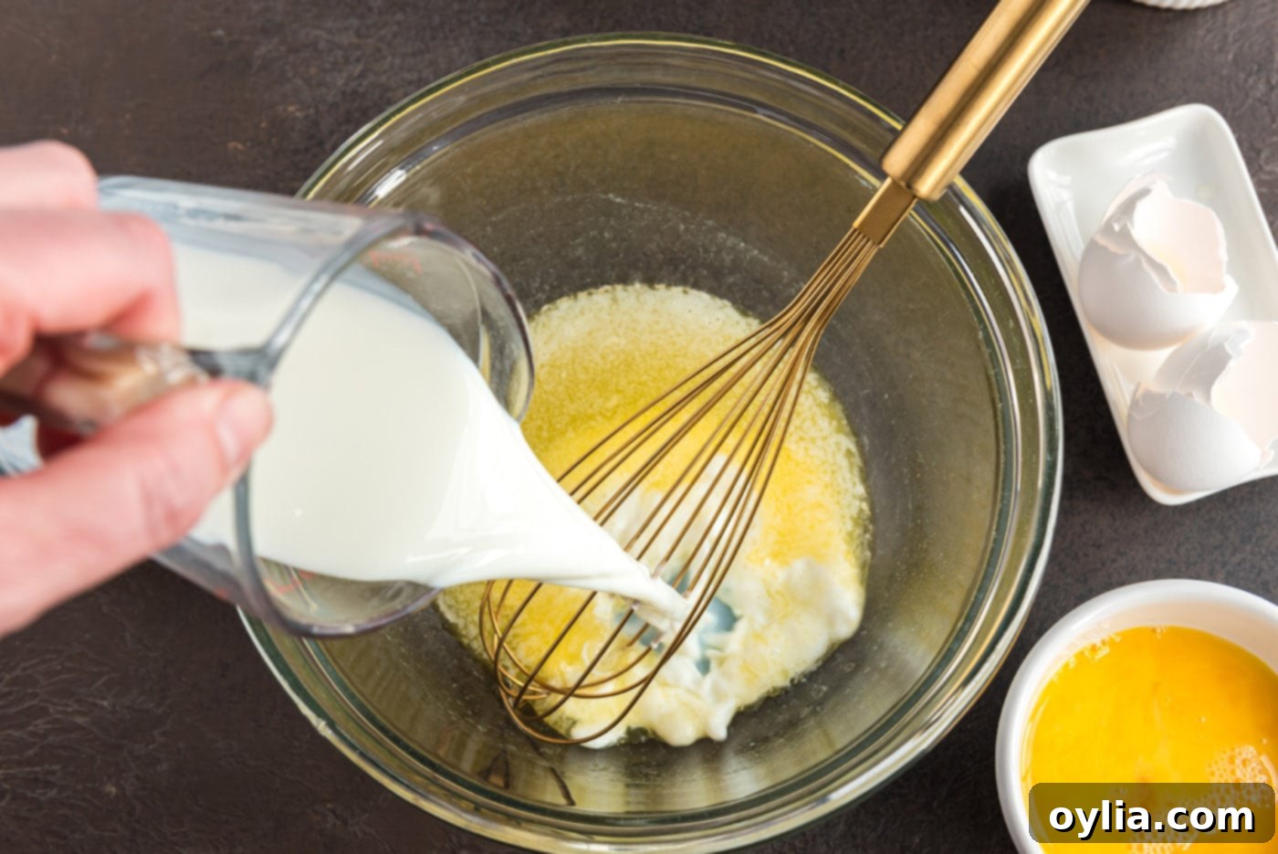 pouring milk into bowl of melted butter