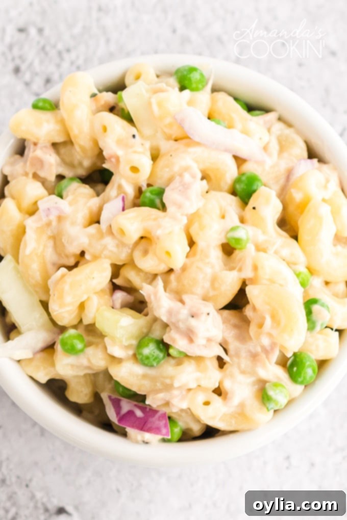 This easy tuna pasta salad recipe is perfect for potlucks and barbecues, or simply a protein-packed and satisfying lunch! Close-up shot of creamy tuna pasta salad with visible macaroni, peas, and celery